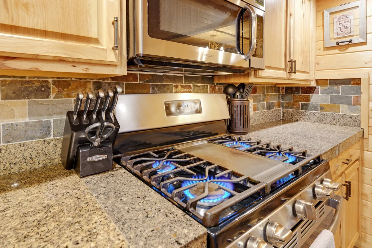 A well-equipped kitchen with a modern stove, ample countertop space, a tidy backsplash, and a knife set. The kitchen exudes a cozy, homey feel and is clearly ready for cooking and social interaction, supporting group meal prep and memorable gatherings.
